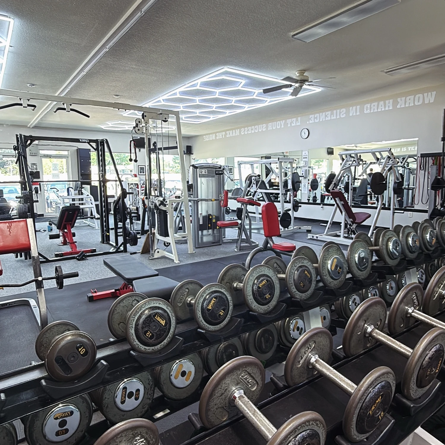 Midwest Iron Addicts gym floor with dumbbells, strength machines and geometric LED ceiling lighting